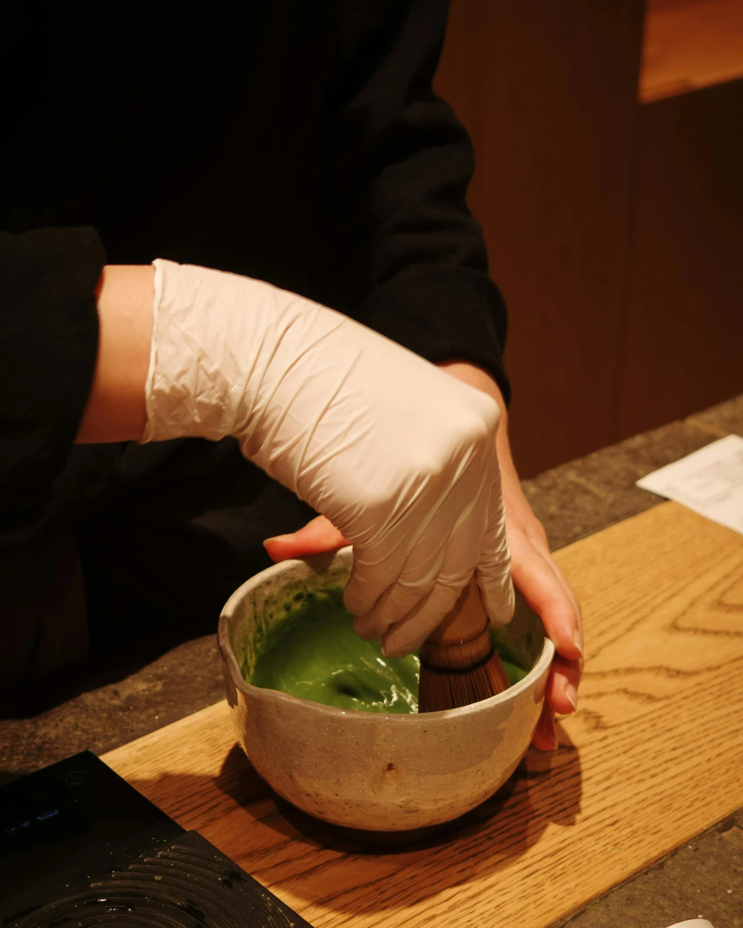Matcha being whisked with a bamboo whisk